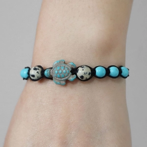 Detail of handmade woven turtle bracelet featuring natural turquoise beads on a wrist