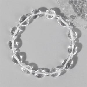 Pulsera minimalista de cristal transparente con cuentas irregulares sobre fondo gris