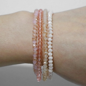Detalle del juego de cuatro pulseras elásticas con cuentas de cristal rosas y blancas