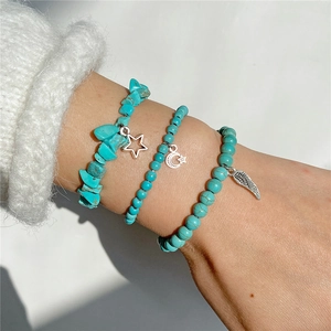 Three-piece turquoise beaded elastic bracelet set with star and leaf charms on wrist