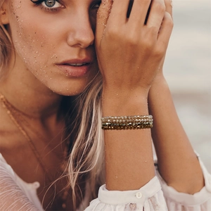 Close-up of bohemian layered crystal bead bracelets in champagne and tawny tones