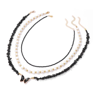 Detailed macro view of triple-layered necklace with black stone beads and butterfly pendant