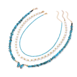 Detailed view of layered necklace with blue butterfly pendant and pearl beads