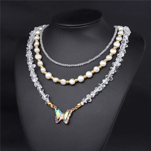 Detailed macro view of triple-layered necklace featuring pearl strands and laser butterfly charm