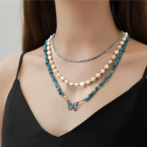 Three-layer necklace with turquoise stones, pearls, and a blue butterfly pendant