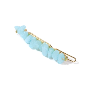 Detail view of gold metal hair clip with blue natural stone chips on white background