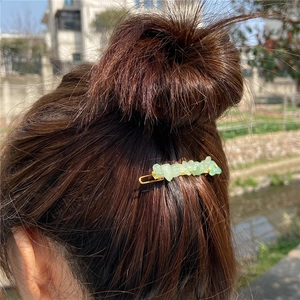 Natural green stone hair clip with gold metal base worn on brunette hair bun