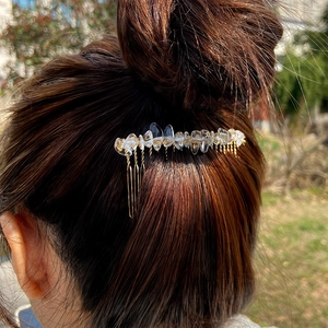 Detail of natural crystal stone hair comb worn on a bun with golden metal base