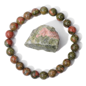 Macro shot of polished Unakite stone bead bracelet with a raw natural mineral stone