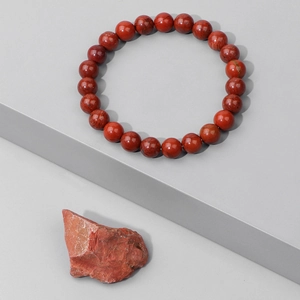 Macro detail of red jasper beaded bracelet with natural stone textures and smooth finish
