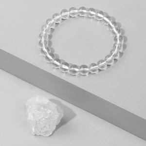 Minimalist clear natural crystal energy bead bracelet with raw stone on a stone stand