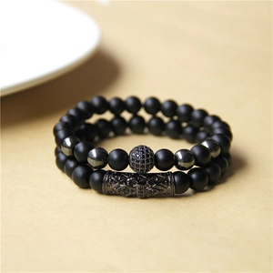 Detailed macro of matte black stone bead bracelets with micro-pave and engraved metal charms