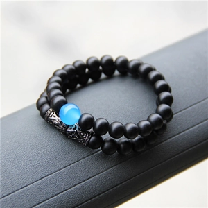 Detail view of double-layer beaded bracelet with matte black stones and blue centerpiece