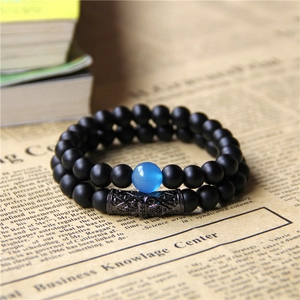 Detail of double-layer beaded bracelet with matte black beads and hollow metal charm