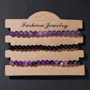 Three-piece natural stone beaded stretch bracelets in purple and black on card