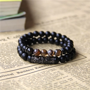 Detail of matte black beads bracelet set with metal carved tube on vintage background