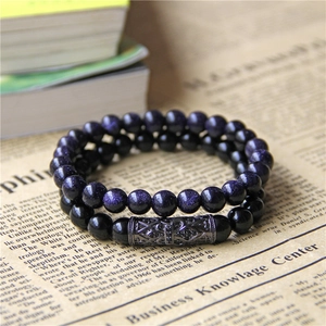 Close-up of blue sandstone and black stone beaded bracelets set on vintage paper