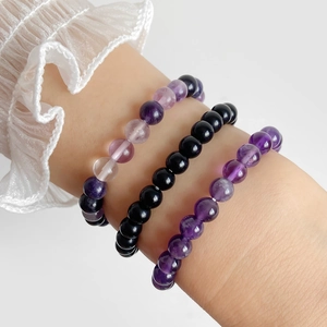 Close-up of three 4mm natural amethyst and fluorite beaded stretch bracelets on a wrist