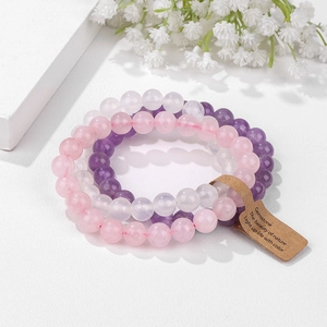 Detailed view of pink, purple, and white stone bead bracelets with a vintage kraft tag
