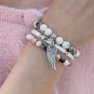 Dettaglio del set di bracciali con perline di marmo bianco e ciondolo ad ala d'argento