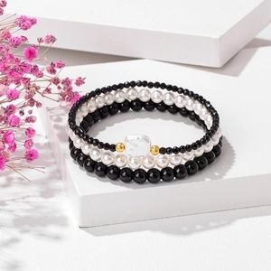 Close-up of a three-piece beaded bracelet set with natural stones and white pearls