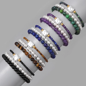 Macro shot of layered natural stone bead bracelets with pearls and gold accents on a display