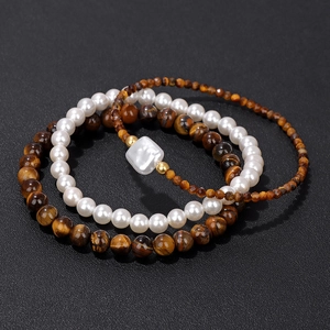 Close-up of three-layer beaded bracelet set featuring tiger eye stones and white pearls