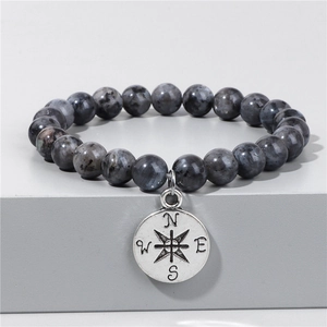 Naturstein-Perlenarmband 8mm mit Vintage-Kompass-Anhänger auf grauem Sockel Hintergrund