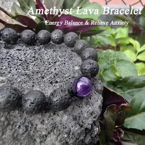 Makroaufnahme Lava-Armband mit Amethystperle auf Lavagestein vor grünen Pflanzen