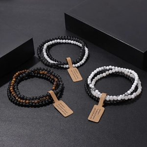 Detail view of 4mm natural stone beaded bracelets set with vintage tags on black stone blocks
