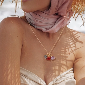 Boho gouden ketting met natuurstenen hangers gedragen door model in vakantiesfeer
