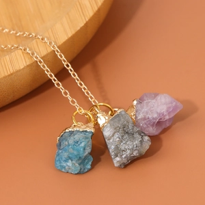 Macro-opname van drie natuurlijke edelsteenhangers aan een gouden bohemien ketting