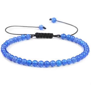 Macro detail of hand-woven bracelet with transparent blue stone beads and adjustable cord
