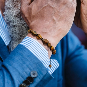Herenarmband van tijgeroog kralen en natuursteen handgeweven gedragen door model
