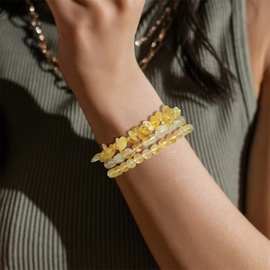 Detail view of a three-piece set of natural yellow crystal bead bracelets on a model wrist