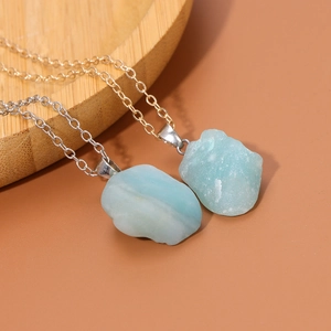 Set di due collane in pietra naturale grezza con catene dorate e argentate su legno