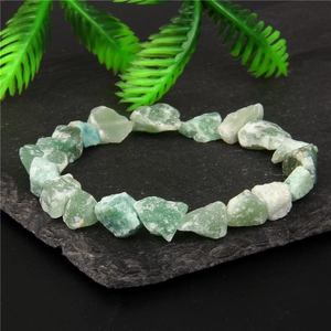 Macro detail of natural irregular green stone beads with white textures on a black rock base