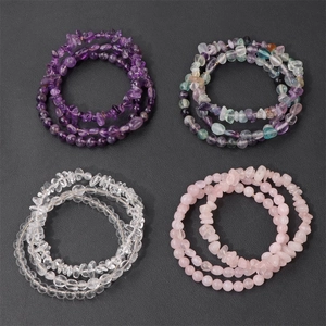 Detail of four layered natural crystal bracelets featuring amethyst and quartz stones