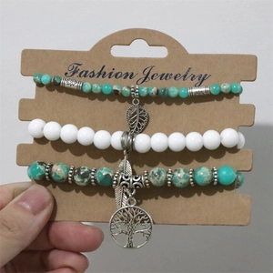 Close-up of tree of life and leaf charms on natural stone bead bracelet set of three