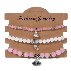 Détail de bracelets en perles roses avec pendentifs de lotus et feuille sur carte