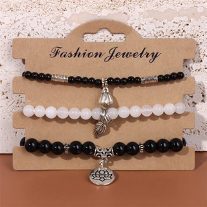 Détail de trois bracelets perlés avec breloques lotus, feuille et arbre sur carte