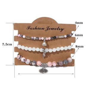 Ensemble de trois bracelets en perles avec pendentifs lotus et feuille sur carte