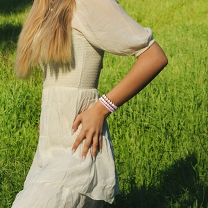 Buitenfoto van een driedelige roze en witte kralenarmbandset met hart- en sterbedels
