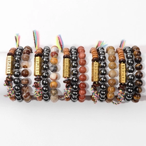 Détail de bracelets en perles superposés avec œil de tigre et mantras gravés dorés