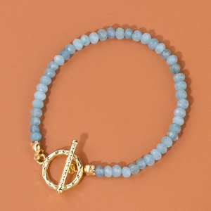 Détail de perles en pierre bleu clair facettées et fermoir à bascule doré sur un bracelet