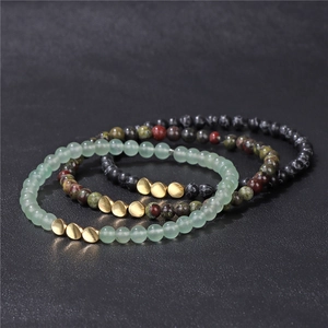 Macro detail of three-piece natural stone bead bracelets with gold spacer accents