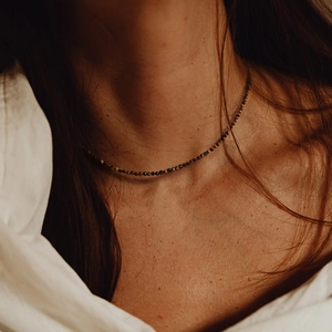 Primer plano de un collar de cuentas de piedra natural facetadas en el cuello del modelo