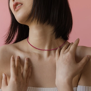 Collar minimalista de cuentas de piedra natural facetada en rojo rosa sobre una modelo