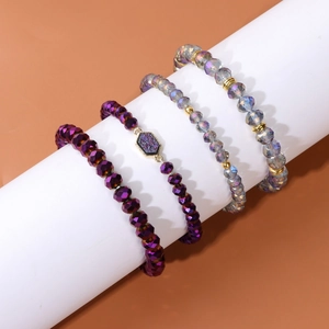 Détail d'un ensemble de quatre bracelets en perles de cristal violet sur un support blanc