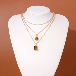 Detailed view of 18k gold triple layered necklace with pearls and tiger eye pendants